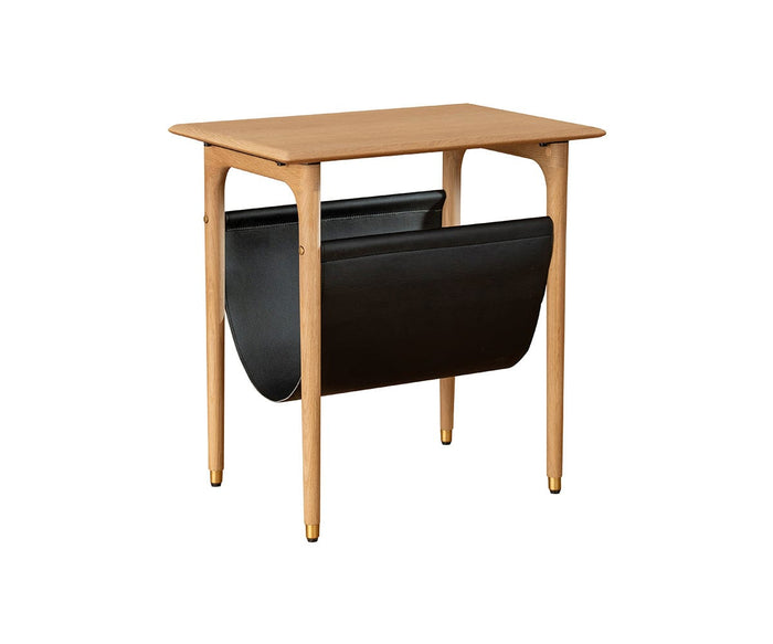 Introducing the Hendrick End Table With Hanging Shelf in White Oak—a compact mid-century piece crafted from solid white oak, featuring elegant tapered legs with brass caps and a stylish black leather hanging shelf underneath, perfect for storing magazines or newspapers.