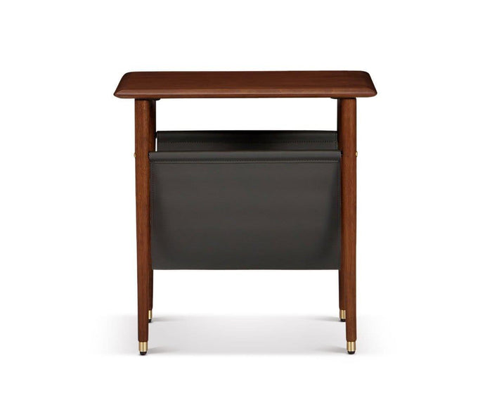 The Hendrick End Table with Hanging Shelf is a mid-century piece crafted from American poplar wood, featuring four tapered legs with brass caps and feet, and a black leather magazine holder suspended between the legs, photographed against a white background.