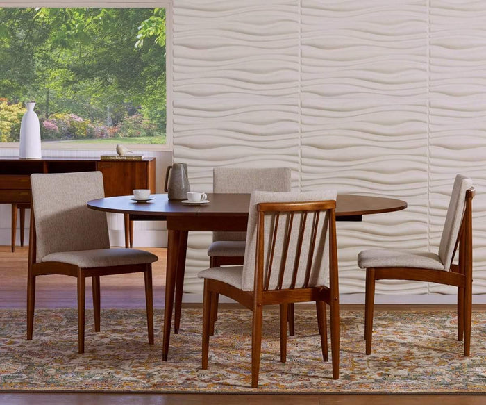 A mid-century modern dining room showcases a round wooden table surrounded by four Holfred Dining Chairs, each upholstered in beige, all set atop a patterned rug. The ambiance is elevated by a wavy textured white wall that channels Scandi-inspired elegance, while a window frames serene greenery outdoors.