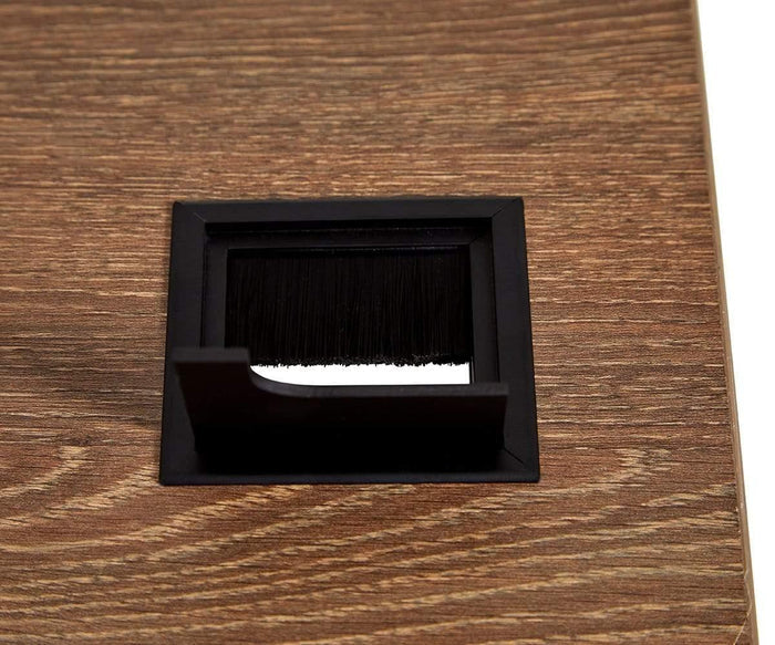 A close-up of a rectangular black cable grommet with a brush insert on a wooden surface, designed to let cables pass through while keeping out dust—an ideal accessory for the Inari 71″ Desk or any modern workspace.