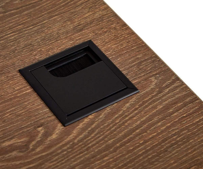 A close-up of a wood-grain Inari 71″ Desk with a black rectangular cable grommet cover, featuring a brush opening for wires to pass through.