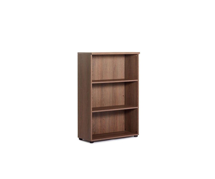 The Inari Low Bookcase is a three-shelf wooden bookcase with a light brown finish, ideal for office storage. It stands on small, black feet and is shown empty against a plain white background.