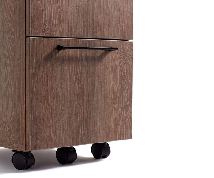 A close-up of the Inari Mobile File Pedestal, featuring a wooden design with a black handle, visible wood grain pattern, and wheels, photographed against a white background.
