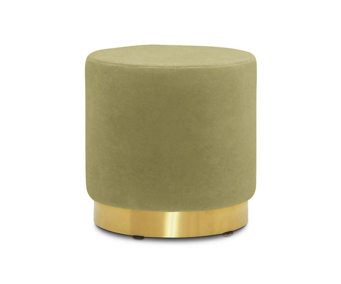 The Isla Ottoman, featuring a compact round shape and green velvet upholstery, is accented with a gleaming brass base and displayed against a plain white background.