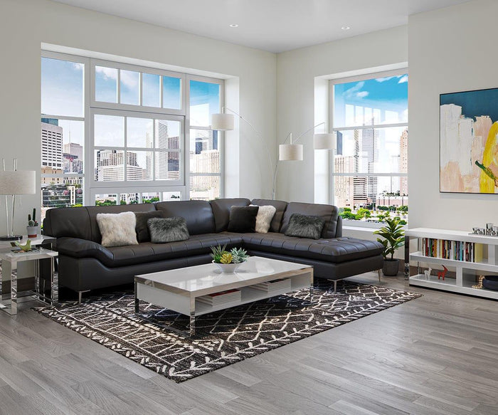 Modern living room with a large sectional sofa, coffee table, geometric rug, bookshelves, and the striking Jan 3-Light Arch Floor Lamp featuring textured fabric shades that provide soft illumination. Standing lamps frame the city view through big windows, complemented by abstract wall art.