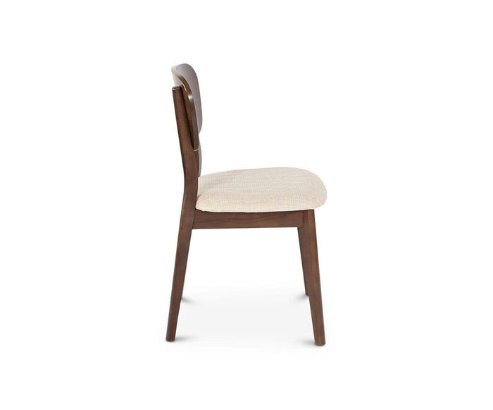 Side view of the Juneau Dining Chair, showcasing its walnut veneer frame, curved wooden backrest, and light beige cream fabric seat, set against a plain white background.