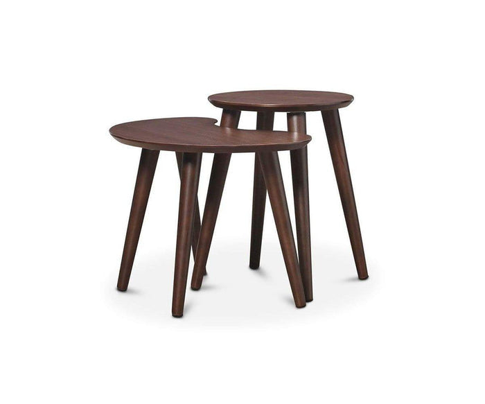 The Juneau Nest Of Tables, featuring two dark wooden side tables with round tops and three-leg mid-century modern design, are positioned side by side on a white background.