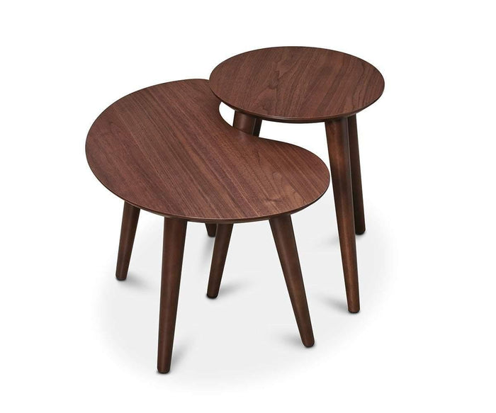Introducing the Juneau Nest Of Tables: a pair of modern wooden nesting tables, each with three legs, perfect for enhancing any living space. The set features a larger, kidney-shaped table and a smaller, round table—both finished in mid-century modern walnut and shown overlapping against a white background.