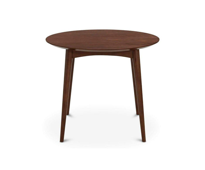 The Juneau Round Table, finished in walnut, features a round wooden top and four slightly angled, tapered legs, showcasing a mid-century modern and Scandinavian design. It is presented against a white background.