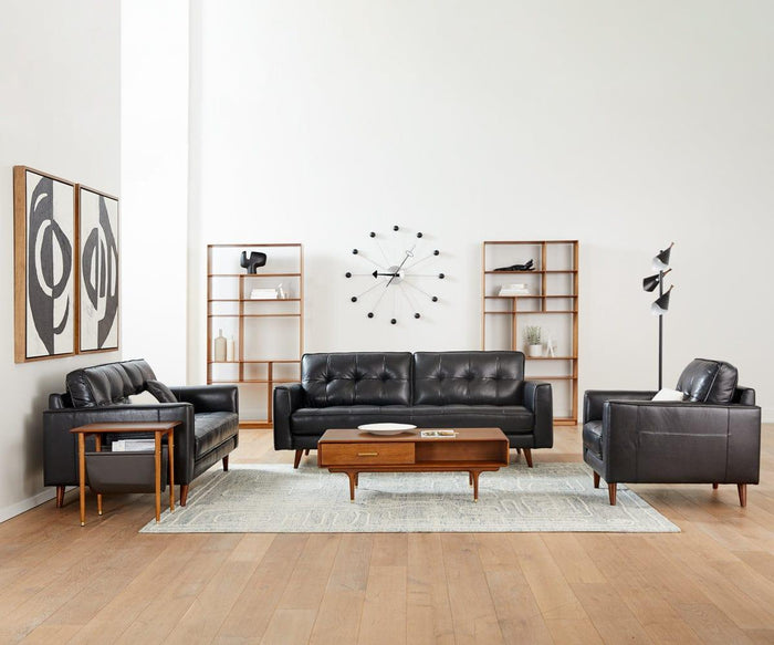 Modern living room with black leather sofas, a wooden coffee table, two bookshelves, abstract wall art, a large clock, the Kabrino Floor Lamp featuring adjustable shades, and a light-colored rug on wood flooring.