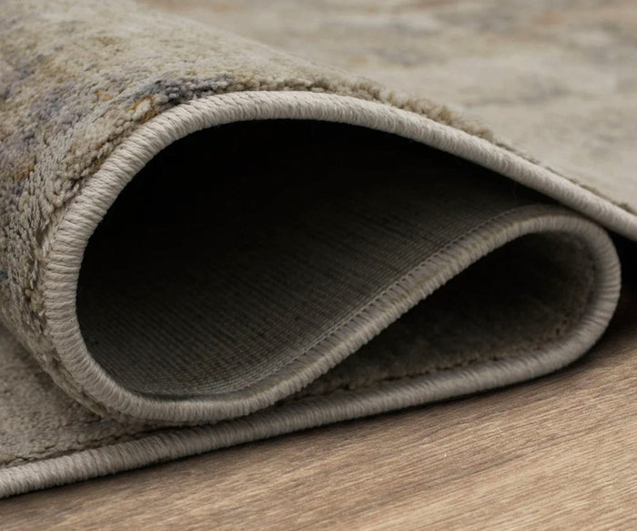 A close-up of the Karastan Echo Tesoro Rug in Cream showcases its durable construction, rounded folded edges, and plush thickness as it rests on a wooden floor, highlighting the rug’s beautifully textured surface.