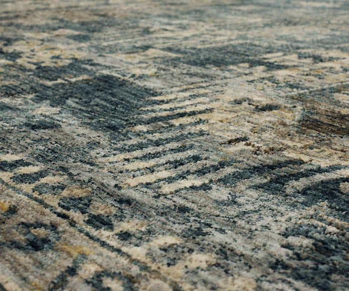 Close-up of the Karastan Marash Karamar Rug in Blue, featuring a textured surface with an abstract, geometric pattern in shades of blue, gray, beige, and cream. The image showcases the rug’s detailed fibers and subtle color variations, highlighting its soft feel and durable construction.