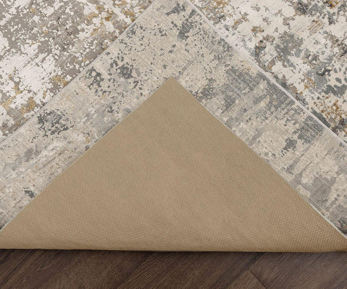 A corner of a patterned area rug is lifted to reveal the Karastan Rug Pad underneath, offering excellent rug protection on the dark wood floor.