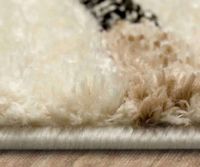 Close-up of the Karastan Traverse Lanes Rug - Tan, a durable polyester rug in cream and beige tones resting on a wooden floor, highlighting its soft, fluffy fibers and detailed stitches along the edge.