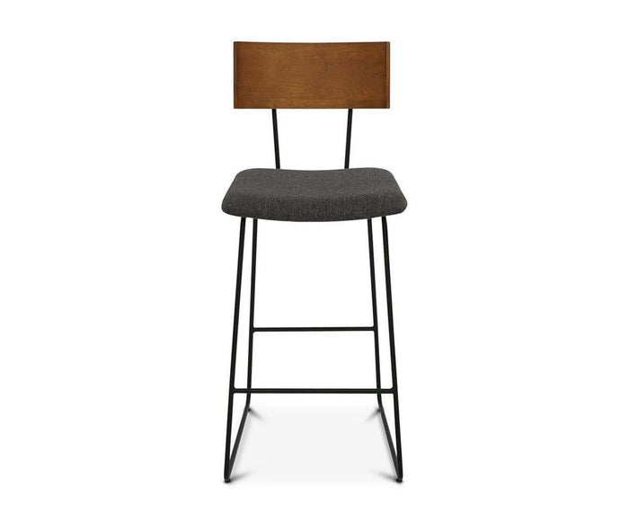 The Karsten Bar Stool showcases a modern industrial design with a wooden backrest, a plush saddle brown cushioned seat, and slender black metal legs, displayed against a white background.