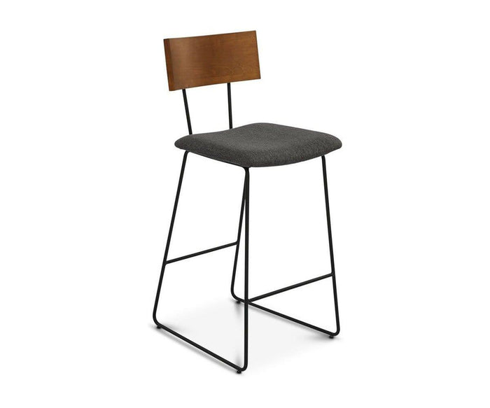 The Karsten Bar Stool features a modern industrial design with a dark wooden backrest, black metal legs, and a cushioned dark gray seat, showcased against a plain white background.