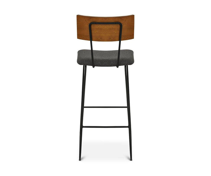 The Karsten Bar Stool is displayed from the back against a white background, highlighting its rustic design with a wooden backrest, gray cushioned seat, and black metal legs.