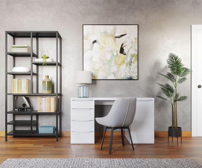 Modern home office with a white desk featuring metal leg support, the Kyla Swivel Dining Chair with a gray cushioned seat, decorative lamp, and abstract wall art. Black shelving holds books and decor, and a potted plant sits on the right. Wood floor and gray rug complete the look.