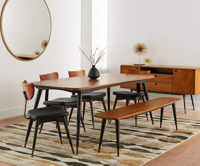 Mid-century modern dining room with a wooden table, four Lanson Dining Chairs featuring black faux leather upholstery and bentwood backrests, a bench, a sideboard, a round mirror, a striped rug, and minimalist decor including a vase with branches and gold decorative objects.