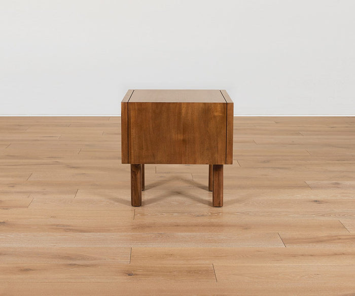 Leevi End Table with a rectangular top and narrow legs, crafted from solid acacia wood as part of the Leevi Collection, shown from a side view on a light wood floor against a plain white wall.