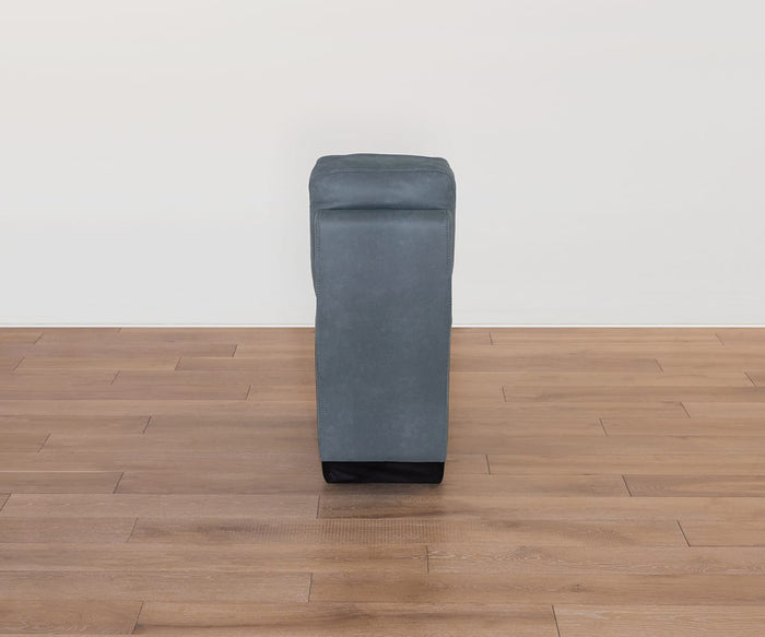 The Lunna Console, featuring a gray rectangular ottoman with a soft, leather-look fabric cushion, is shown on a wooden floor against a plain white wall and viewed from the narrow end—illustrating its versatile modular design.