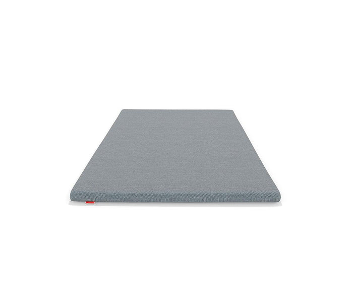 The Mattress Topper, featuring a rectangular and thin grey design, is displayed on a white background from a low-angle view at the foot of the topper.