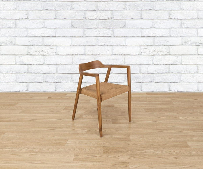 A Melina Chair sits on a light wood floor against a white brick wall.