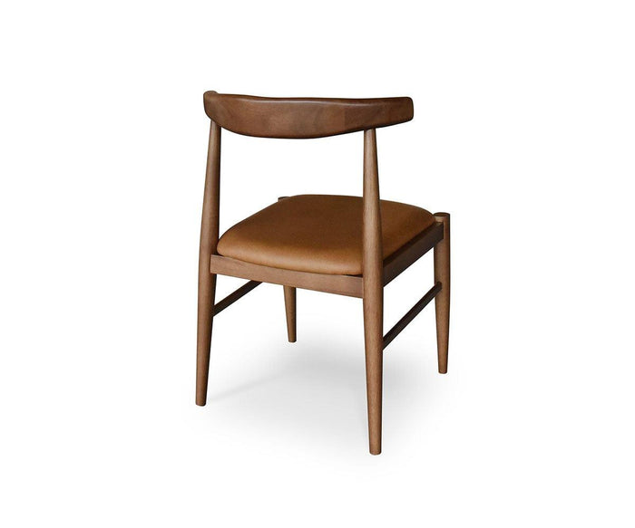 The Miles Leather Dining Chair features a Danish modern design with a curved backrest and a brown cushioned seat, shown from behind at an angle against a white background.