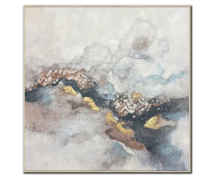 The Mineral Glow Wall Art features a multi-colored abstract design with soft gray, beige, and blue tones. Jagged lines and textured gold accents run diagonally across the hand-painted canvas, creating a sense of movement and depth. It is finished with a thin, light-colored frame for a modern touch.