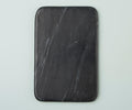 The Mirco Black Marble Slab, a rectangular black marble cutting board with rounded corners and subtle white streaks that mimic a handcrafted aesthetic, is displayed on a light gray surface.