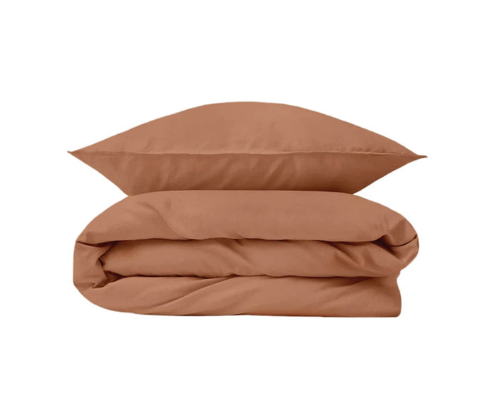 A Mocha Duvet Cover, crafted from organic cotton bed linen, is neatly folded with a matching brown pillow stacked on top, both set against a plain white background.