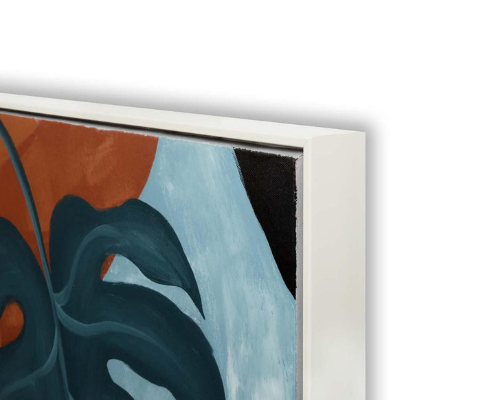 Close-up of the “Moonlit Monstera Oil Painting,” featuring dark green leaves against a background divided between rusty orange and pale blue. The white frame surrounds the canvas, with the hand-painted edges of the artwork visible.