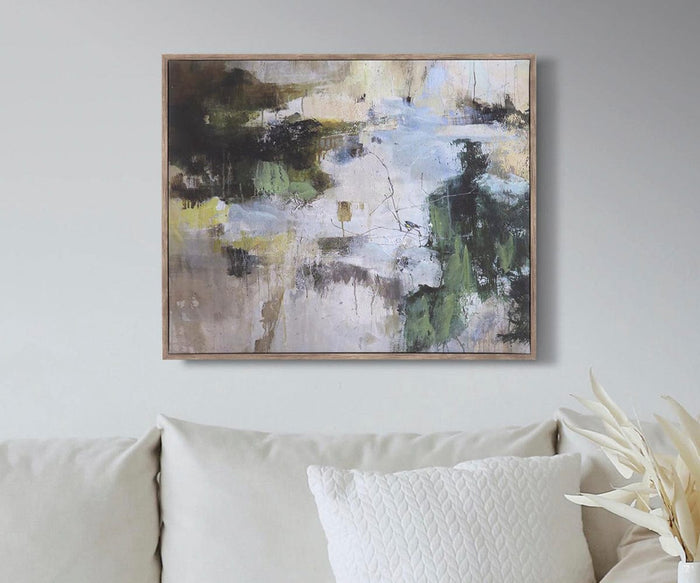 The Nature Walk Wall Art, a striking piece featuring dark, green, white, and yellow tones, is displayed on a light gray wall above a cream sofa adorned with a textured white pillow and complemented by dried plants in the corner. This stunning giclée print adds vibrancy and sophistication to the living space.