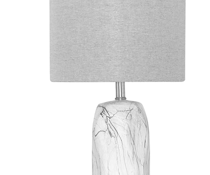 The Nemling Table Lamp features a round, gray linen drum shade and a white ceramic body with a marble pattern. Its base displays subtle dark gray veining, providing a modern and elegant look.