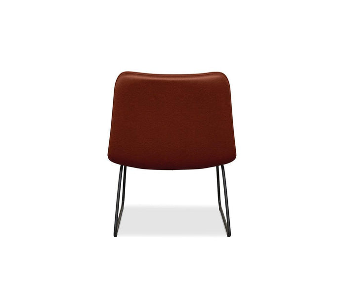 The Oken Lounge Chair is a modern, minimalist armless lounge chair featuring a rust-colored cushioned back and seat, viewed from behind and supported by slender black metal legs on a white background—ideal for adding comfortable seating to any contemporary space.