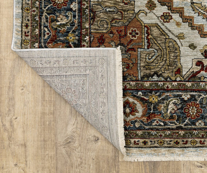 An Oriental Weavers Aberdeen / 1144W Rug in earthy tones is spread across a wooden floor. One corner is turned over to reveal the intricate detailing on the backside, bringing a subtle boho charm to the space.