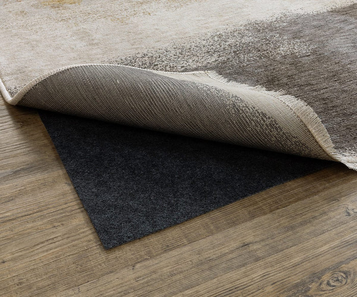 A rug corner is lifted to reveal the Oriental Weavers All-N-One / 0004E Rug Pad beneath, offering non-slip support and floor protection on a wooden surface.