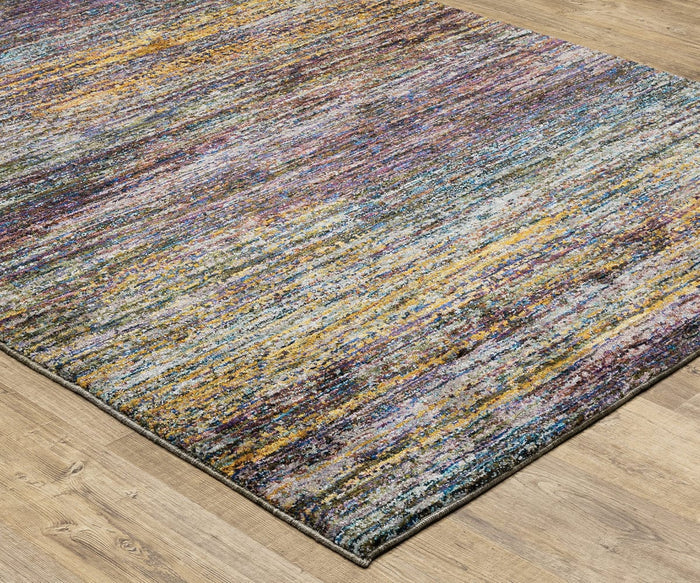 The Oriental Weavers Atlas / 8037B Rug, shown here on a wooden floor, displays a vibrant mix of yellow, purple, blue, and gray hues. This durable, machine-woven area rug features a textured abstract pattern and partially covers the flooring in the image.