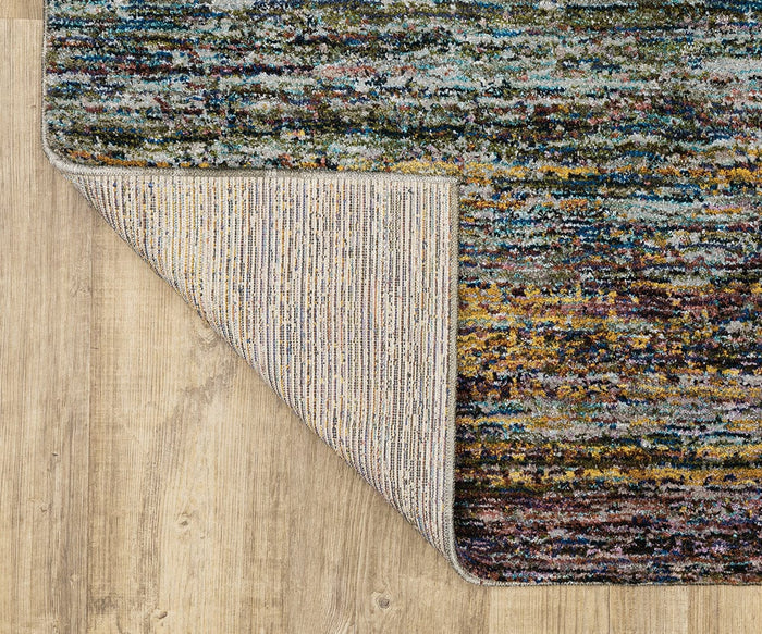 The Oriental Weavers Atlas / 8037B Rug, a multicolored machine-woven piece from the Atlas Collection, is displayed on a light wood floor with one corner flipped to show its beige and striped underside—a stylish and durable area rug perfect for any space.