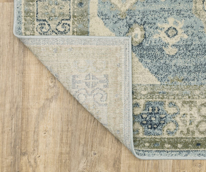 The Oriental Weavers Branson / BR03A Rug, featuring a blue and beige pattern and distinct modern motifs, is power-loomed and displayed on a light wood floor with one corner folded over to reveal the back, highlighting its contemporary appeal.