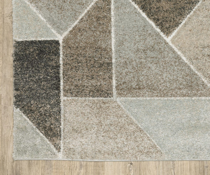 The Oriental Weavers Cambria / 4L Rug, featuring geometric overlapping shapes in neutral tones of beige, brown, black, and gray, is placed on a light wood floor. Crafted from durable polypropylene yarn with a high pile, this rug brings comfort and contemporary style to any space.