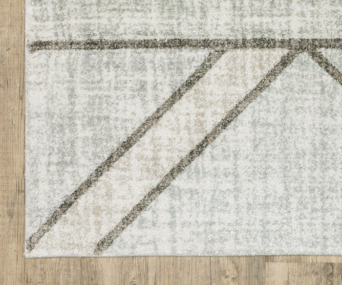 A close-up of a corner of the light-colored Oriental Weavers Cambria / 5569B Rug, showcasing abstract gray and beige lines crafted from soft polypropylene yarn, elegantly placed on a wooden floor.