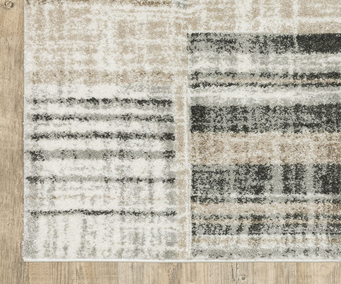 A close-up of the Oriental Weavers Cambria / 55X Rug, a rectangular area rug crafted from soft polypropylene yarn, showcasing a modern abstract plaid design in beige, black, gray, and white hues. This high-pile rug is elegantly laid on a light wooden floor.