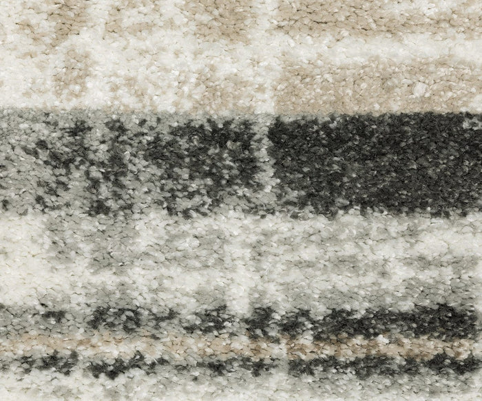 Close-up of a textured Oriental Weavers Cambria / 55X Rug featuring horizontal stripes in cream, beige, gray, and black. The high-pile fibers look soft and plush, accentuating the pattern and smooth color transitions.