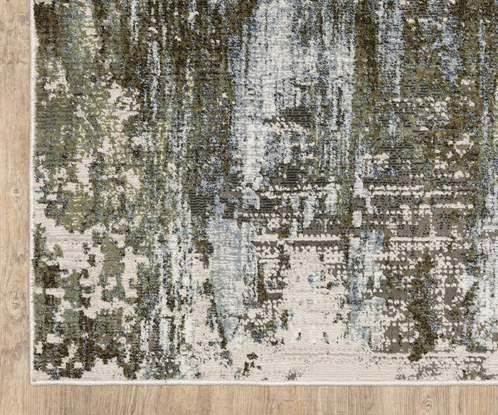 A close-up of the Oriental Weavers Caravan / 2060F Rug showcases its abstract, nature-inspired pattern in green, blue, gray, and cream tones atop a wooden floor. Part of the Caravan Collection and crafted from space-dyed polyester, this rug features a modern design reminiscent of brushstrokes or pixelated shapes for a textured appearance.
