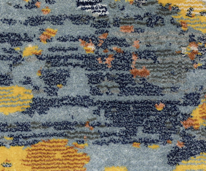 Abstract pattern featuring blue, yellow, gray, and orange patches on a textured surface reminiscent of fabric. Inspired by nature, this design presents irregular shapes and overlapping colors for a dynamic, layered look—reflecting the signature style of the Oriental Weavers Caravan / 530V Rug with its space-dyed polyester construction.