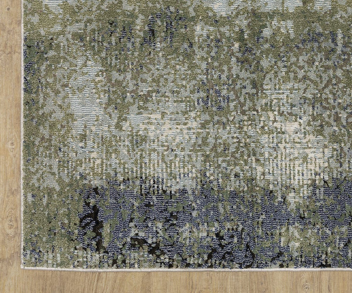 A close-up of the corner of the Oriental Weavers Caravan 5571H rug, showcasing its green, blue, and beige textured surface with an abstract, nature-inspired pattern crafted from space-dyed polyester, placed on a light wood floor.