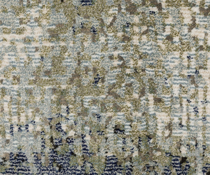 A close-up view of the Oriental Weavers Caravan 5571H Rug showcases its nature-inspired, irregular pattern in blue, beige, green, and gray hues, rendered in space-dyed polyester for a pixelated textured effect.