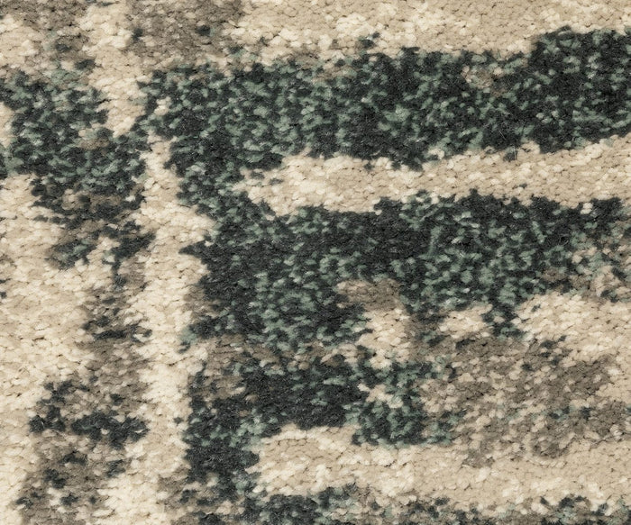 Close-up of the Oriental Weavers Carson / 745C Rug, showcasing its contemporary abstract pattern in green, black, beige, and cream. This rug from the Carson Collection features a soft, plush texture and a design inspired by natural stone or camouflage.
