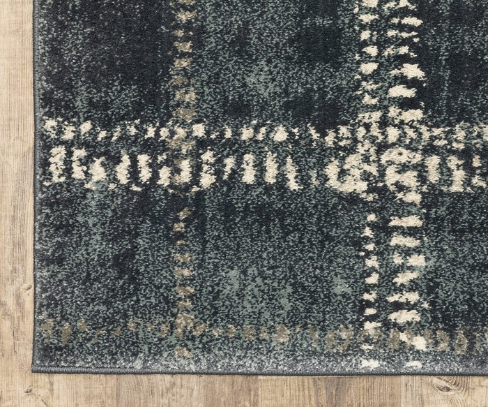 Close-up of the Oriental Weavers Carson / 746J Rug from the Carson Collection, featuring a plaid pattern in dark green, cream, and gray tones on a wooden floor. This contemporary area rug is made from durable polypropylene and offers a soft, slightly distressed look with irregular line details.